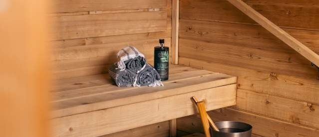 Perinteisen puusaunan lauteet, pyyherulla ja löylyämpäri