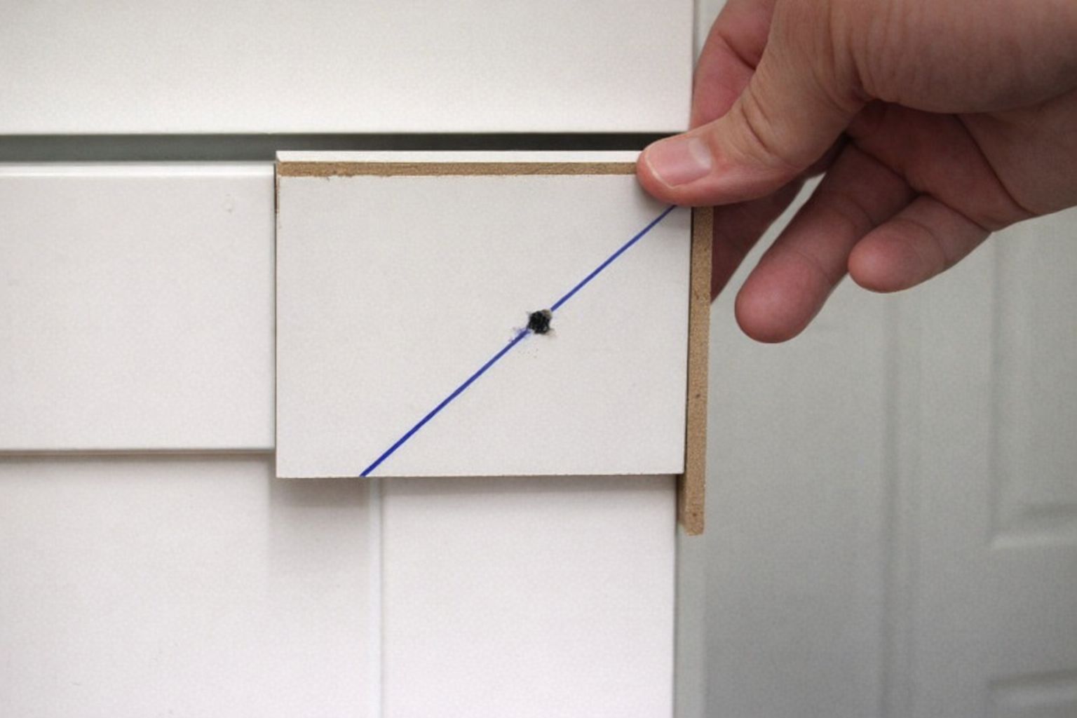 Käsin tehty sapluuna kaapin nupin porauskohdan merkitsemiseen.