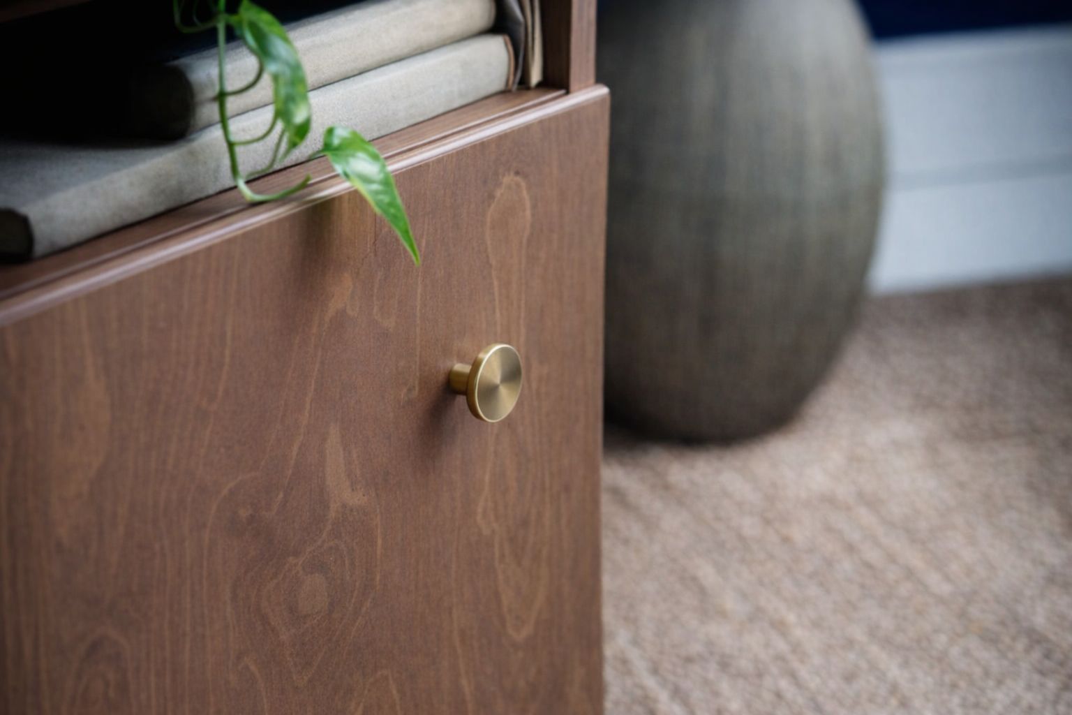 Pyöreä messinkinen nuppi puunvärisessä kaapin ovessa.