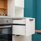 Mustat modernit keittiövetimet valkoisissa ja turkooseissa kaapeissa.