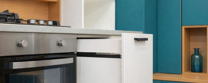 Mustat modernit keittiövetimet valkoisissa ja turkooseissa kaapeissa.