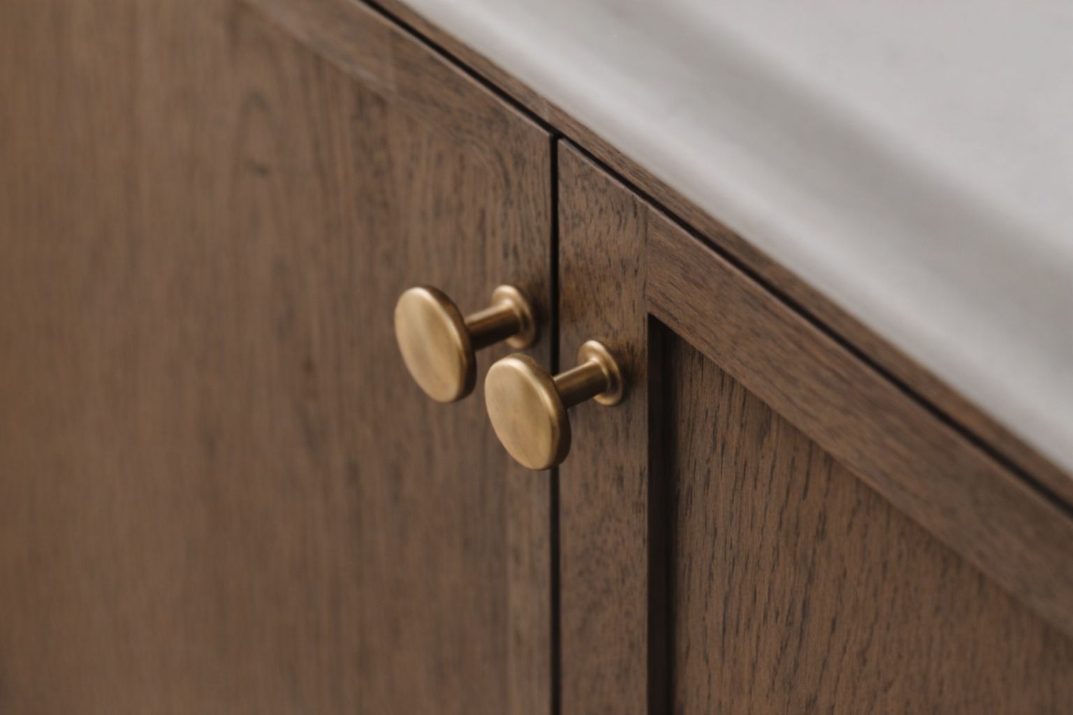 Pyöreät messinkiset vetimet tummissa puisissa keittiökaapeissa.